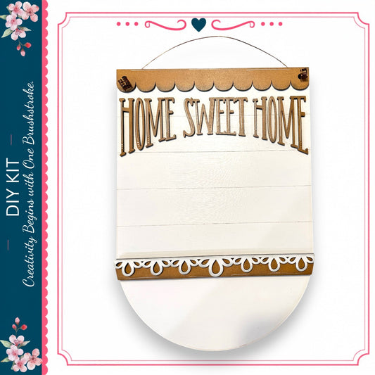 a wooden sign with the text "HOME SWEET HOME" written on it. The sign is hanging on a wall and appears to be a DIY kit.
