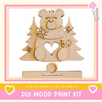 a DIY wood paint kit, with a wooden bear figure and pine trees as the main decorative elements.