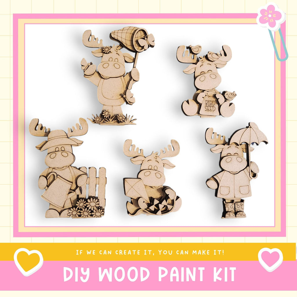 a DIY wood paint kit with five wooden animal figurines, including moose, deer, and other woodland creatures, each holding various objects such as a hat, umbrella, and flower.