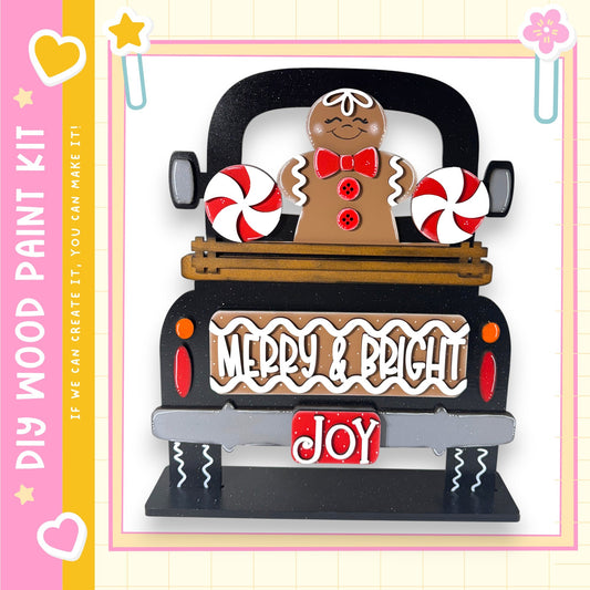 A black truck with a gingerbread man and candy decorations, including red and white striped candy canes, on the back.