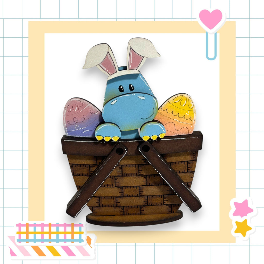 A blue Easter bunny with white ears and a brown basket sits in a basket, surrounded by colorful Easter eggs.