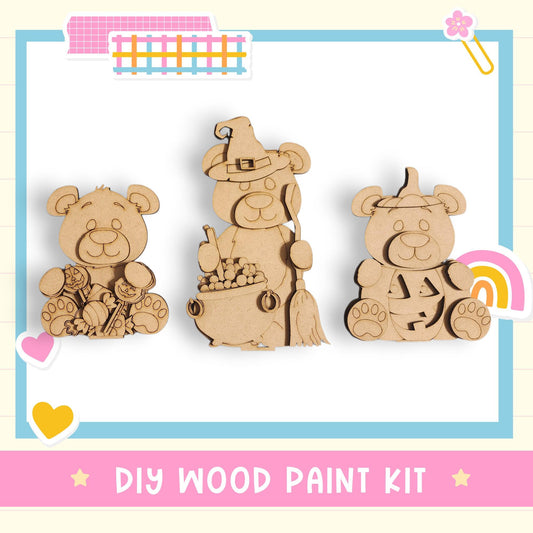 three wooden bear figurines, each with a unique outfit or accessory, arranged in a row. The bears are depicted in a playful and whimsical manner, suggesting a DIY wood paint kit for creating similar bear-themed decorations or toys.