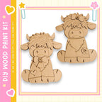two wooden cutouts of cows, one on the left and one on the right, sitting on the ground.