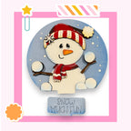 A snowman wearing a red and white striped hat and scarf, with a carrot nose and two snowballs, is depicted against a blue background with a pink border.