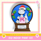 A wooden snow globe with a cartoon dinosaur wearing a Santa hat and holding a gift box, surrounded by holly leaves and berries.