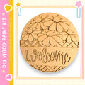 a wooden sign with the word "Welcome" carved into it. The sign is surrounded by a decorative border and is displayed against a pink and yellow background.
