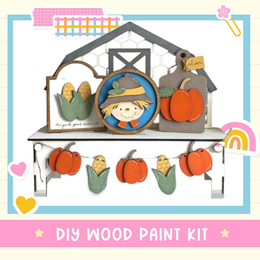 The image is a DIY wood paint kit featuring a scarecrow, pumpkins, and a barn. The kit includes a scarecrow, pumpkins, and a barn, all made of wood and painted in a decorative style.