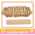 The image is a DIY wood paint kit advertisement, featuring a wooden sign with the text "SHAKE your shamrocks" and a blank wooden board.