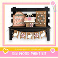 A DIY wood paint kit for creating Easter decorations, including a sign, a wreath, and a banner with wooden rabbits.