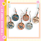A collection of five wooden ornaments with various holiday-themed sayings hanging from strings.