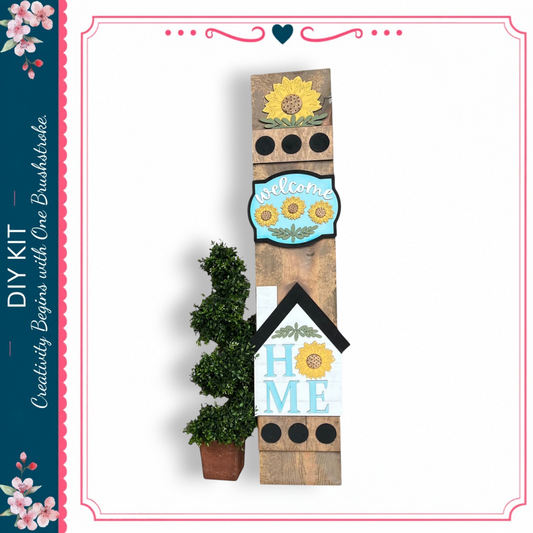 a wooden sign with a sunflower design, a potted plant, and a blue sign with the word "welcome" on it.