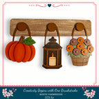 a rustic farmhouse-style DIY kit with a lantern, a basket of flowers, and a pumpkin, all hanging on a wooden board.