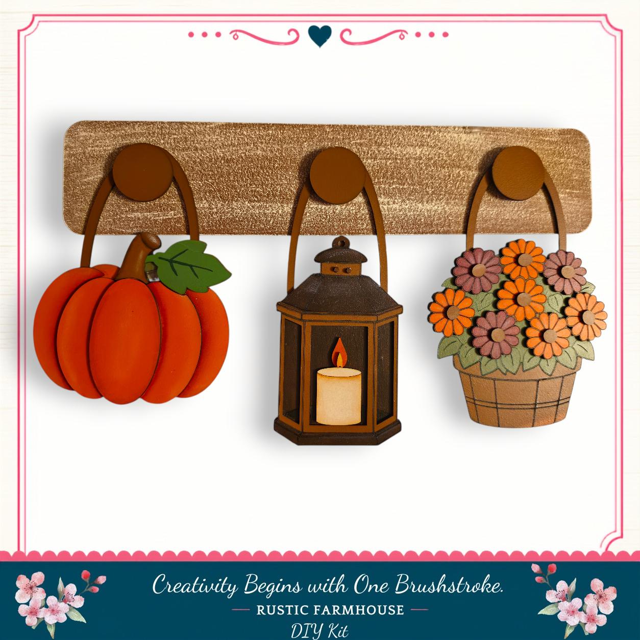 a rustic farmhouse-style DIY kit with a lantern, a basket of flowers, and a pumpkin, all hanging on a wooden board.