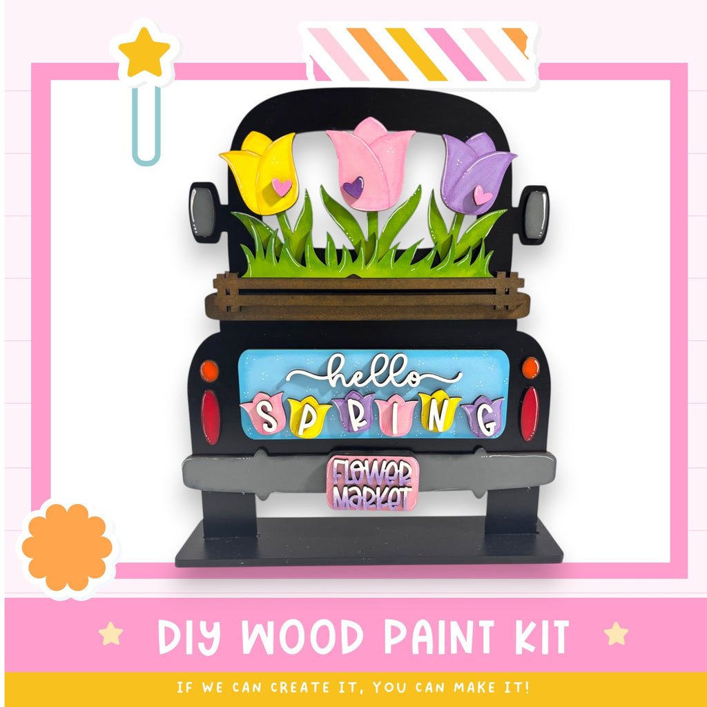 A colorful wooden truck with a floral design on the back, featuring a sign that says "Hello Spring" and the words "Flower Market" below it.