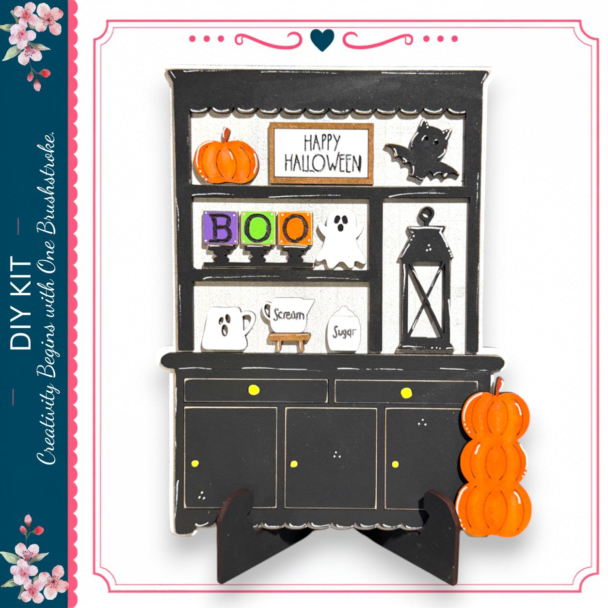 The image is a Halloween-themed DIY kit, featuring a black wooden cabinet with various Halloween-themed decorations and items such as a pumpkin, ghost, and broom.