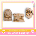 three wooden ornaments with various designs, including a Santa Claus figure, a pair of boots, and a tag with the word "Merry". The image also includes text that says "DIY WOOD PAINT KIT" and "IF WE CAN CREATE IT, YOU CAN MAKE IT!"