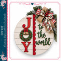 a festive holiday wreath with the word "Joy" written on it, surrounded by red berries and a bow.