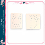 two square pieces of paper with a pattern of small holes or dots on them, arranged side by side.