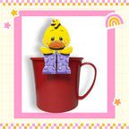 A yellow duck figurine is sitting inside a red mug, which is placed on a pink and white checkered background.