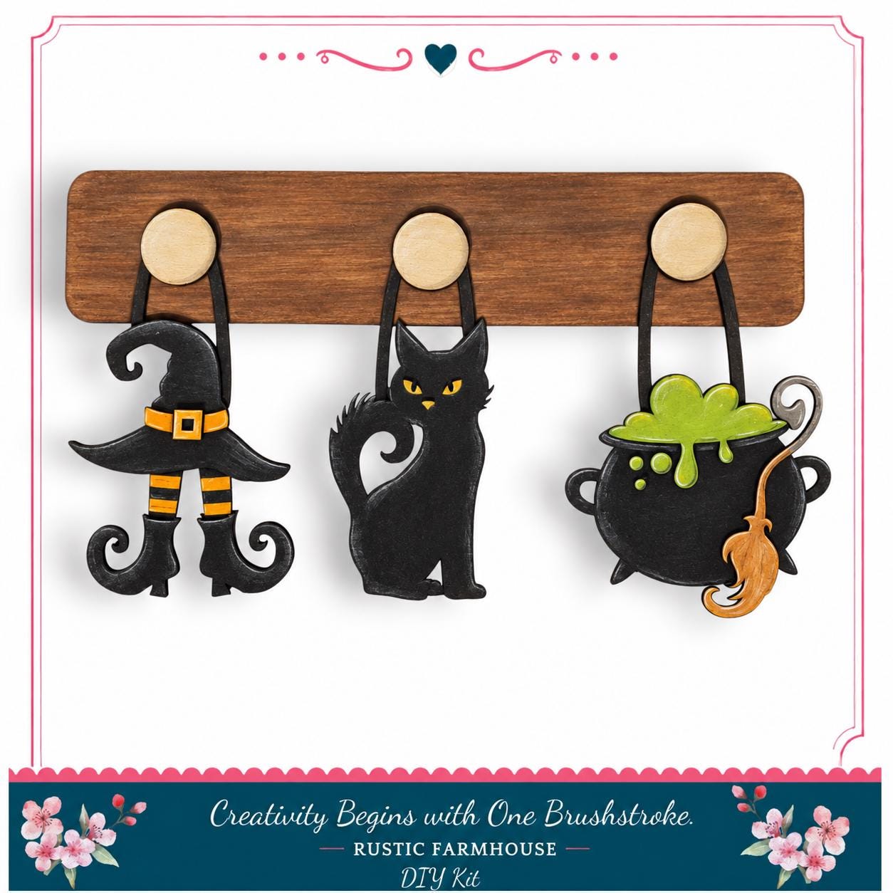 A DIY kit featuring a wooden board with three Halloween-themed charms hanging from it, including a witch's hat, a black cat, and a cauldron with a green substance.