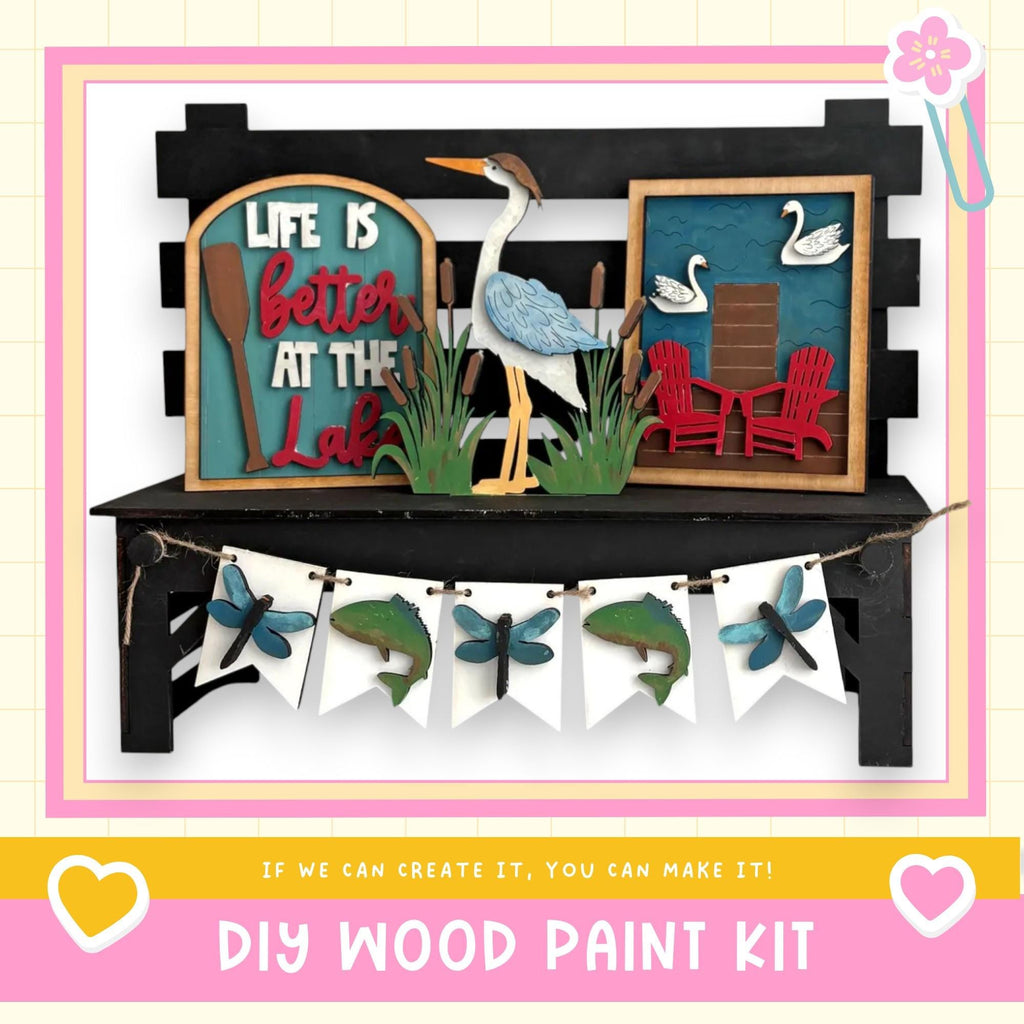 The image is a DIY wood paint kit featuring a wooden bench with a bird, a sign that says "Life is better at the lake", and a banner with various wooden and paper elements.
