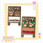 two wooden signs with holiday-themed decorations, including moose heads and Christmas-related text. The signs are set against a grid background with various colorful stickers and a heart-shaped object.
