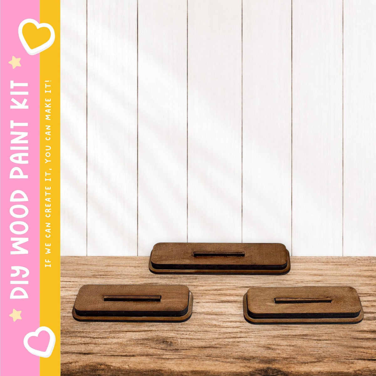 three wooden blocks or stands placed on a wooden surface, with a pink and yellow striped border on the left side.