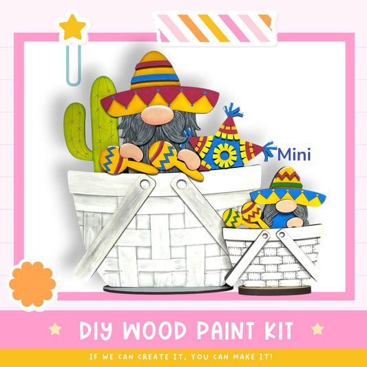 The image is a colorful illustration featuring two gnomes wearing sombreros and hats, sitting in a basket. The background is a pink and white color scheme with a star and a flower. The image includes text that reads "DIY WOOD PAINT KIT" and "IF WE CAN CREATE IT, YOU CAN MAKE IT!"