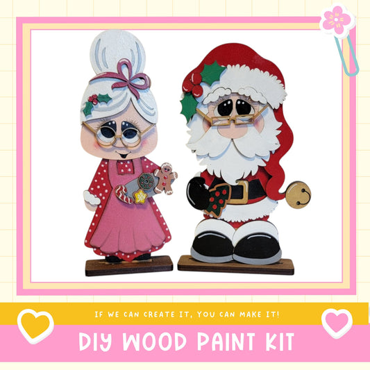 two wooden Santa Claus figurines, one standing and one sitting, with a DIY wood paint kit labeled "DIY WOOD PAINT KIT" in the background.