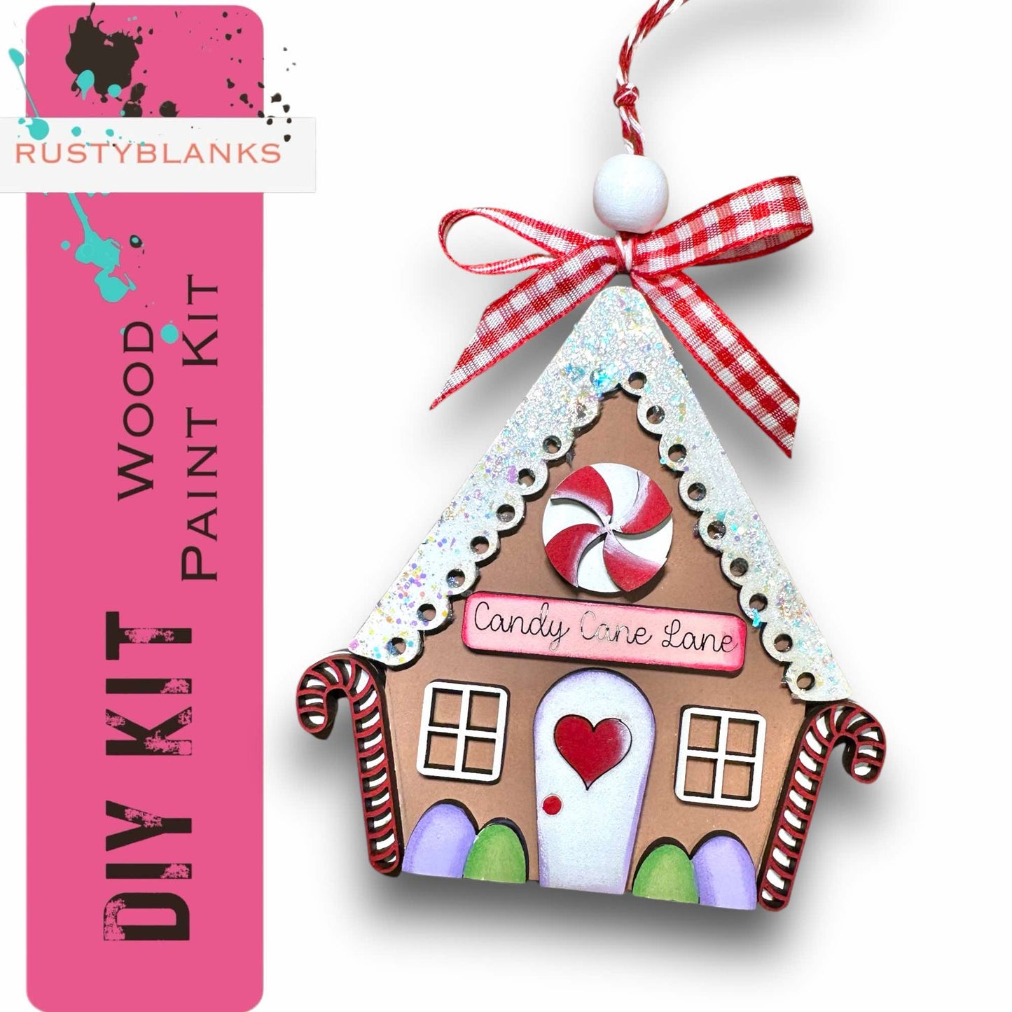 a gingerbread house ornament hanging from a pink ribbon