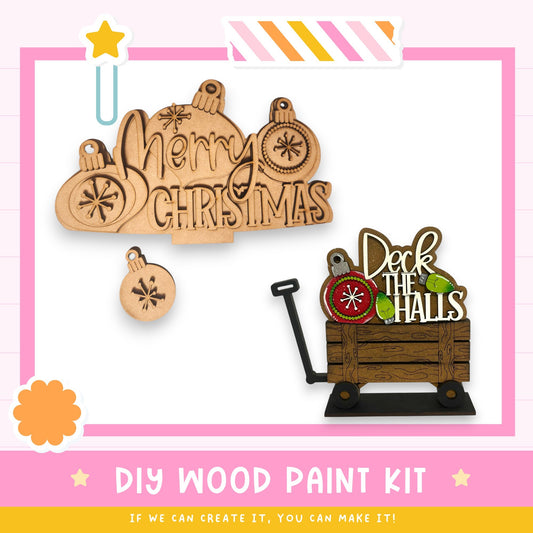 The image is a promotional poster for a DIY wood paint kit, featuring various wooden ornaments and a wooden wagon with a sign that says "Deck the Halls".