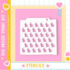 The image is a colorful and playful advertisement for a DIY paint kit featuring a white stencil with a pattern of pink hearts and stars.
