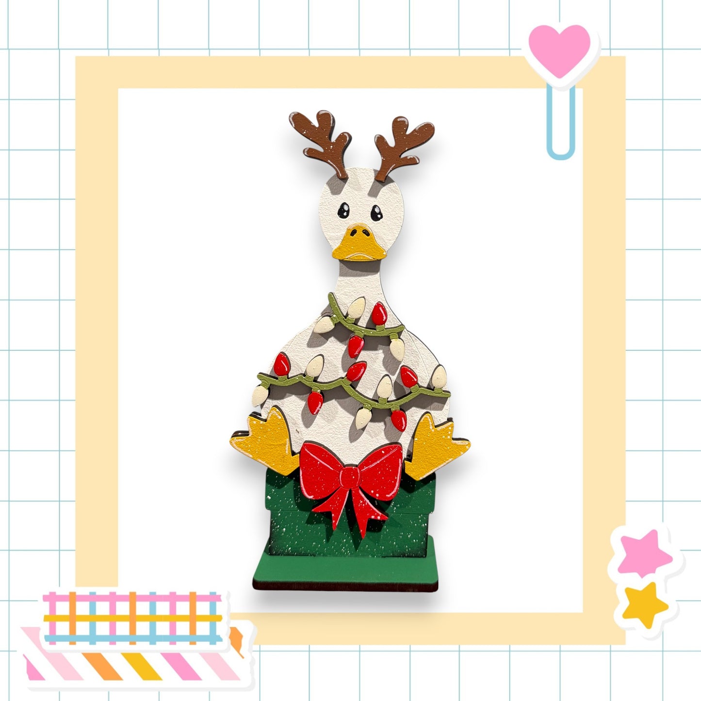 A wooden reindeer figure with antlers and a bow, surrounded by Christmas lights and decorations, is the central focus of the image.