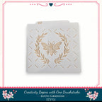 A white stencil with a bee design and a wreath pattern on it, placed against a white background.
