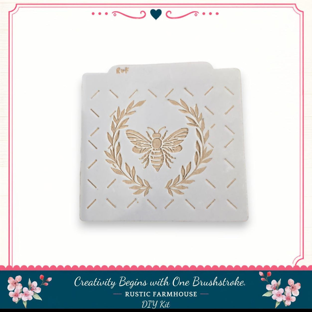 A white stencil with a bee design and a wreath pattern on it, placed against a white background.
