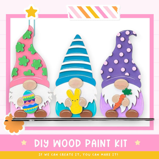 three colorful gnome figurines, each holding an Easter egg and carrot, arranged in a row against a pink background.