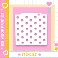 The image is a colorful and playful DIY paint kit featuring a white stencil with a pattern of pink dots on a pink background.