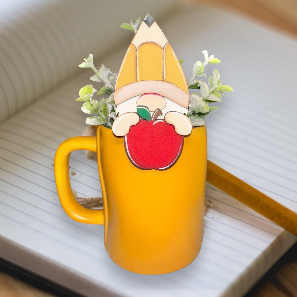 a yellow coffee mug with an apple on top of it