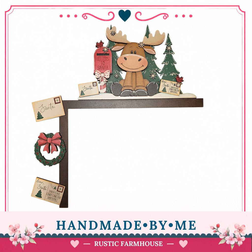A hand-made wooden decoration featuring a moose sitting on a shelf surrounded by Christmas-themed items such as a wreath, a mailbox, and a "Santa" card.