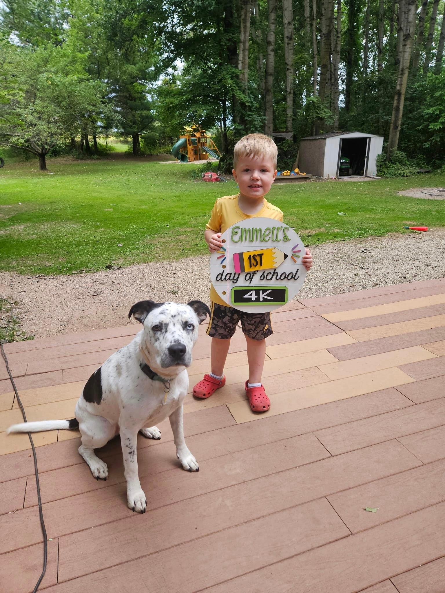 a young boy holding a sign next to a dog