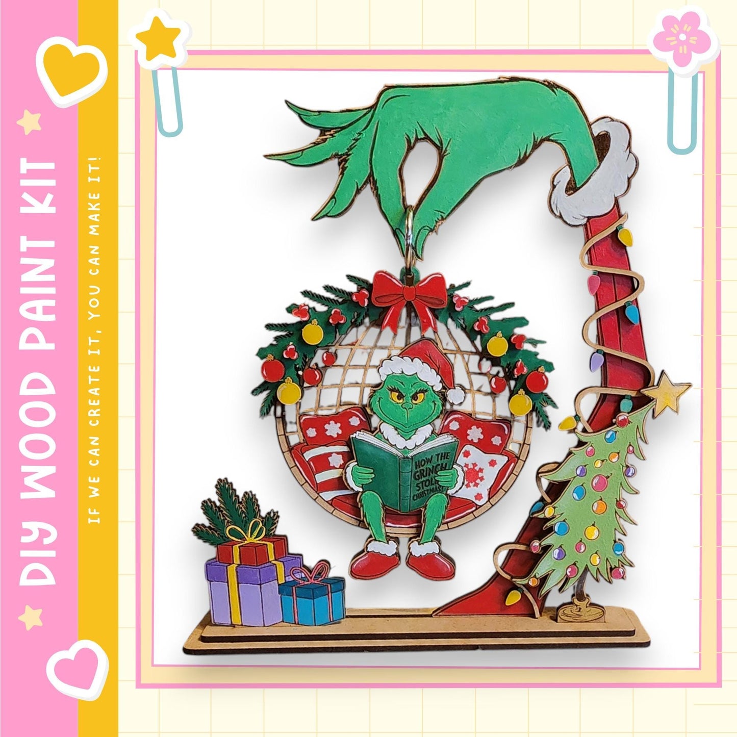 A hand-painted Christmas ornament featuring a green Grinch-like character holding a book, surrounded by holiday decorations such as a wreath, presents, and a Christmas tree.