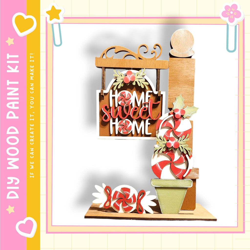 The image is a colorful and festive display featuring a wooden sign that says "Home Sweet Home", surrounded by various candy-like items such as candy canes, peppermints, and other sweets.