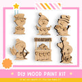 The image is a DIY wood paint kit featuring six wooden snowman or snow angel figures, each with unique designs and accessories. The kit appears to be made of wood and is designed for painting.