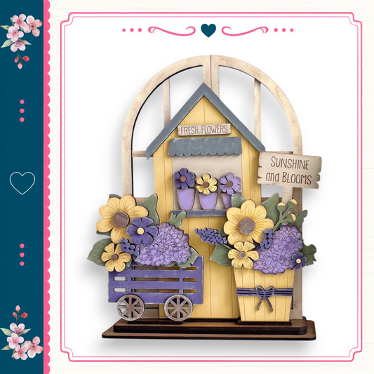 A wooden flower shop with a yellow roof, surrounded by a variety of colorful flowers and plants.