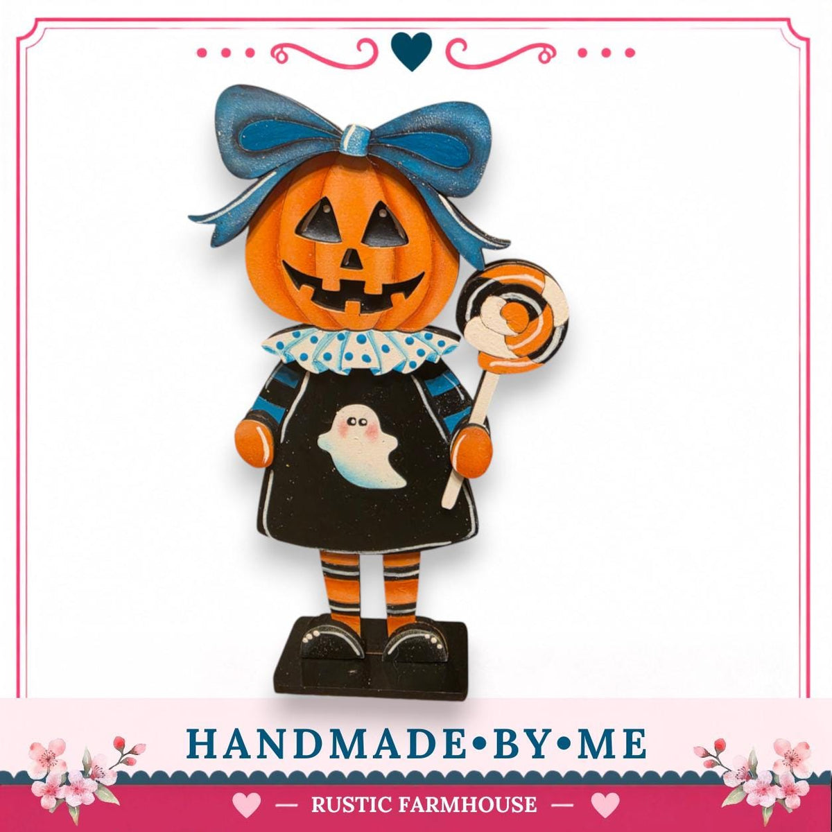 A carved pumpkin figure wearing a black dress with a ghost and holding a lollipop, standing on a black base.
