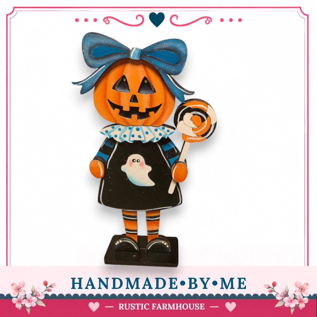 A carved pumpkin figure wearing a black dress with a ghost and holding a lollipop, standing on a black base.