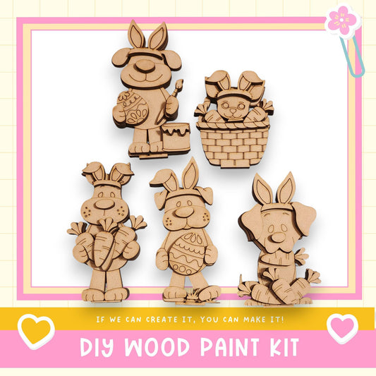 a DIY wood paint kit for creating wooden Easter bunny decorations. There are five wooden Easter bunny figures, each with unique designs and accessories, displayed against a pink and white background.