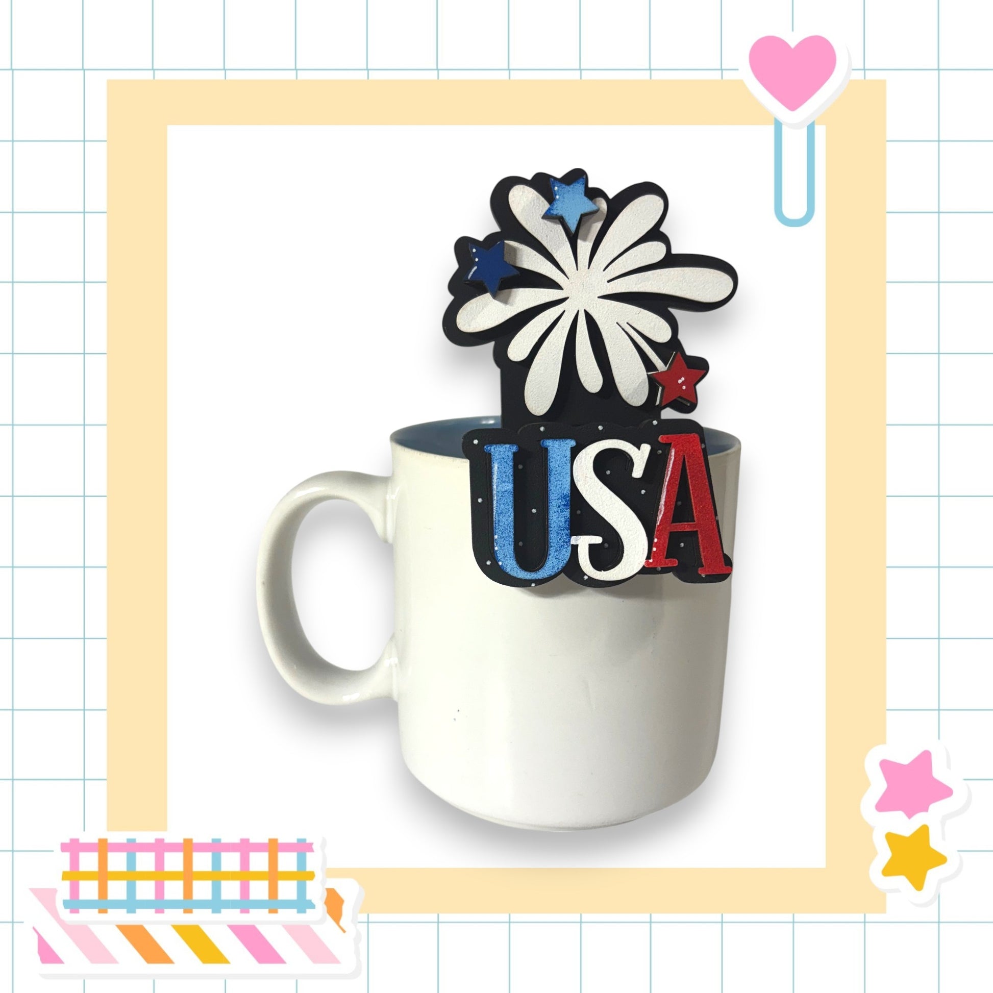 A white mug with the word "USA" written on it, surrounded by various colorful and decorative elements such as stars, hearts, and a rocket ship.