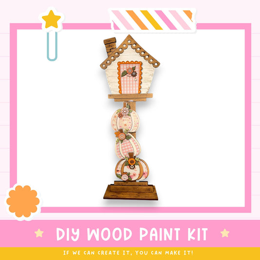 a DIY wood paint kit, which includes a wooden house-shaped object with a roof and a chimney, as well as a wooden base with decorative elements. The kit is presented in a pink and white color scheme, and the text "DIY WOOD PAINT KIT" is prominently displayed. The kit is designed to allow users to create their own wooden house-shaped objects, and the caption encourages creativity and the ability to make it.