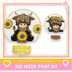 The image is a DIY wood paint kit featuring a wooden cow and sunflowers. The cow is holding a sunflower, and there is a sign that says "If we can create it, you can make it!" The kit appears to be made of wood and is designed for creating wooden objects, such as a wooden cow and sunflowers.